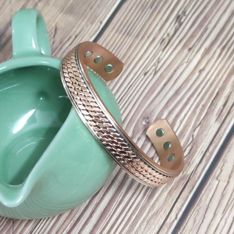 Textured copper bracelet with a polished finish, capturing the intricate woven pattern and metallic sheen.